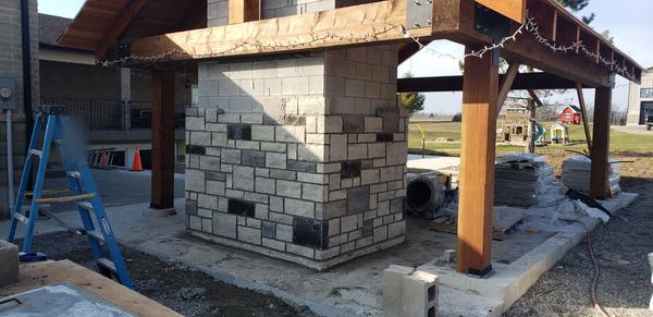 Stone-clad outdoor fireplace under a timber pavilion